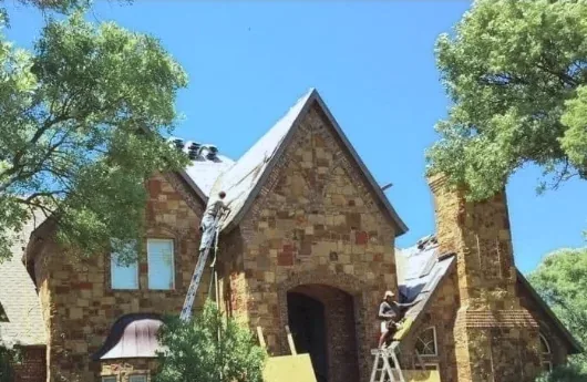 The Mataska crew on ladders and up on the roof of a stone house in Wichita Falls